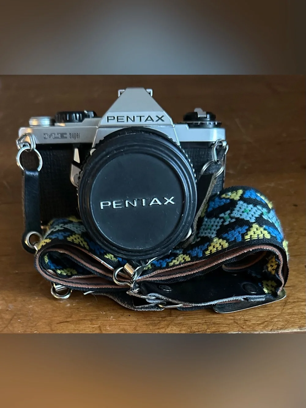 Pentax Silver and Black SLR Camera with Black Lens Cap and Colorful Strap